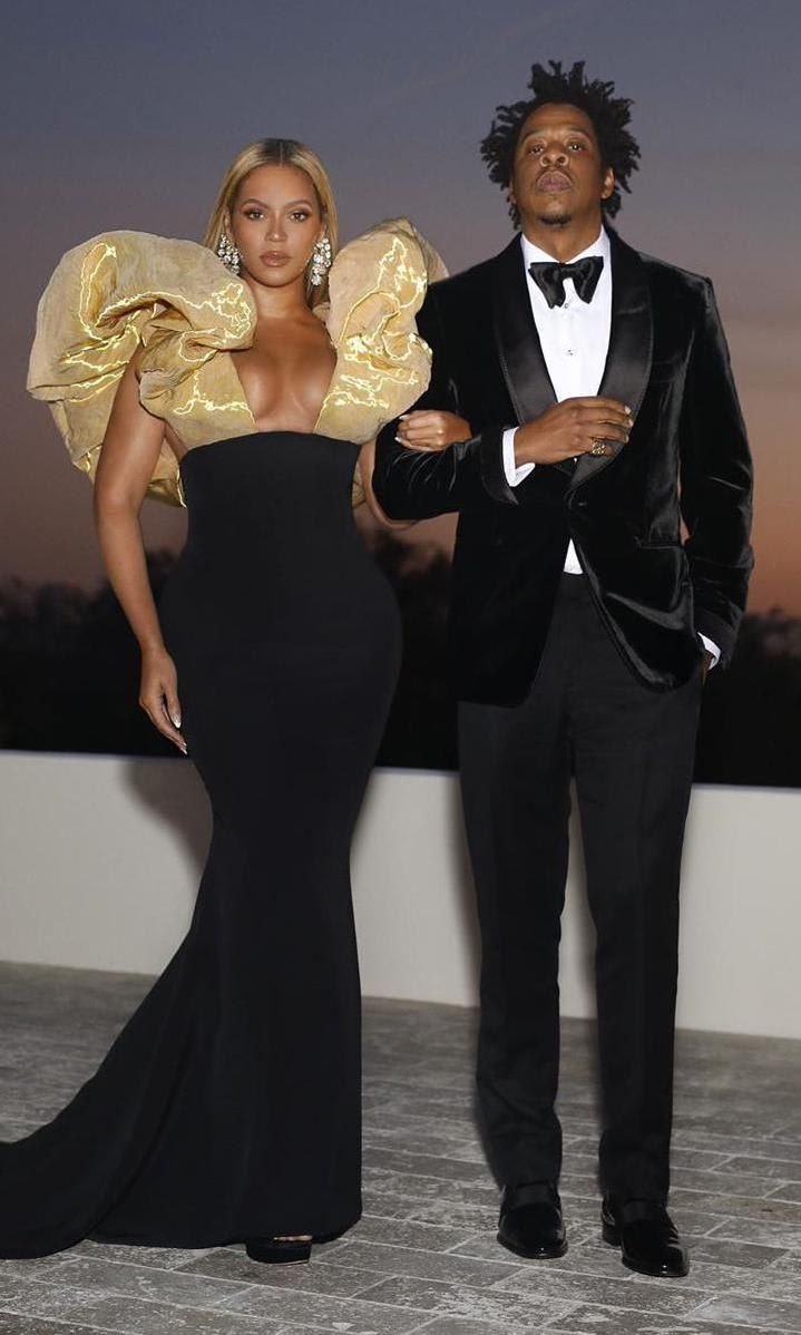 Beyonce in a black dress with over-sized golden sleeves and Jay-Z in a black and white velvet suit