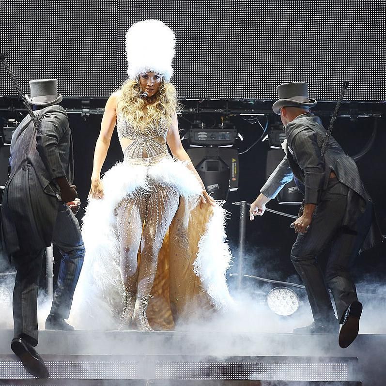 Jennifer Lopez in a silver bodysuit with white feather skirt and hat