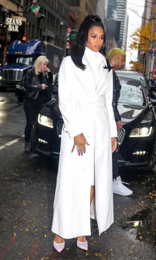 Ciara with a long, white coat, dress and pumps