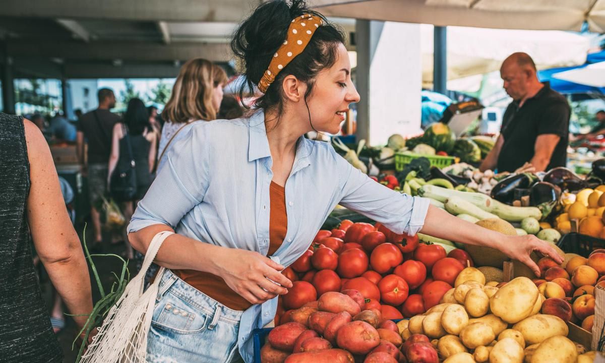 A young housewife buys vegetables at the market.