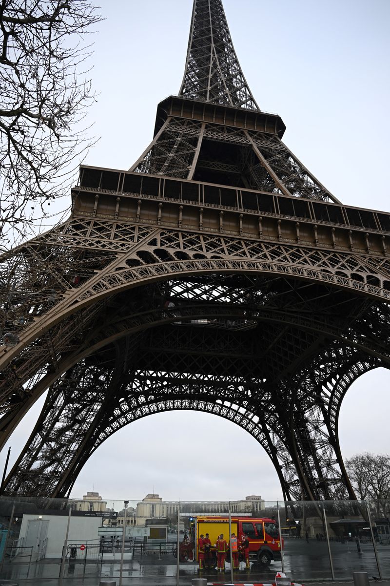 Los bomberos franceses se encuentran alrededor de su vehículo al pie de la Torre Eiffel, donde se informó de un incendio en París, el 24 de diciembre de 2024. (Foto de Anna KURTH/AFP) (Foto de ANNA KURTH/AFP vía Getty Images)