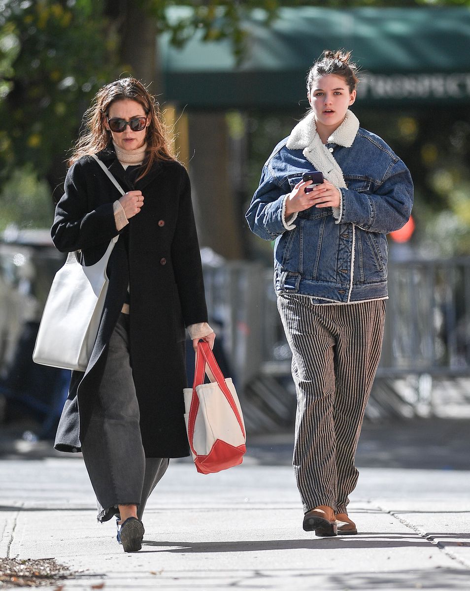 Katie Holmes and Suri Cruise strolled around New York City. The stunt duo was seen together for the first time since Suri left for college. The 18-year-old wore a shearling-lined denim jacket, striped pants, and brown boots. Katie wore a black trench coat, a sweater, baggy pants, and Mary Jane flats.