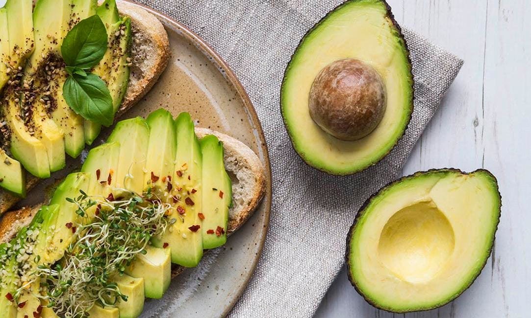 A platter of delicious avocado toast topped with basil and seasoning.