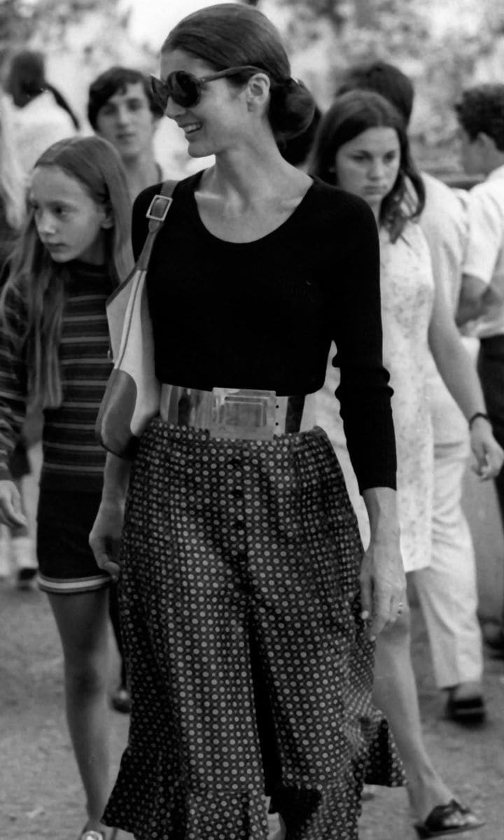 Jackie enjoyed an Italian holiday in Capri wearing a printed skirt, scoop neck black top, oversized belt and shades.)