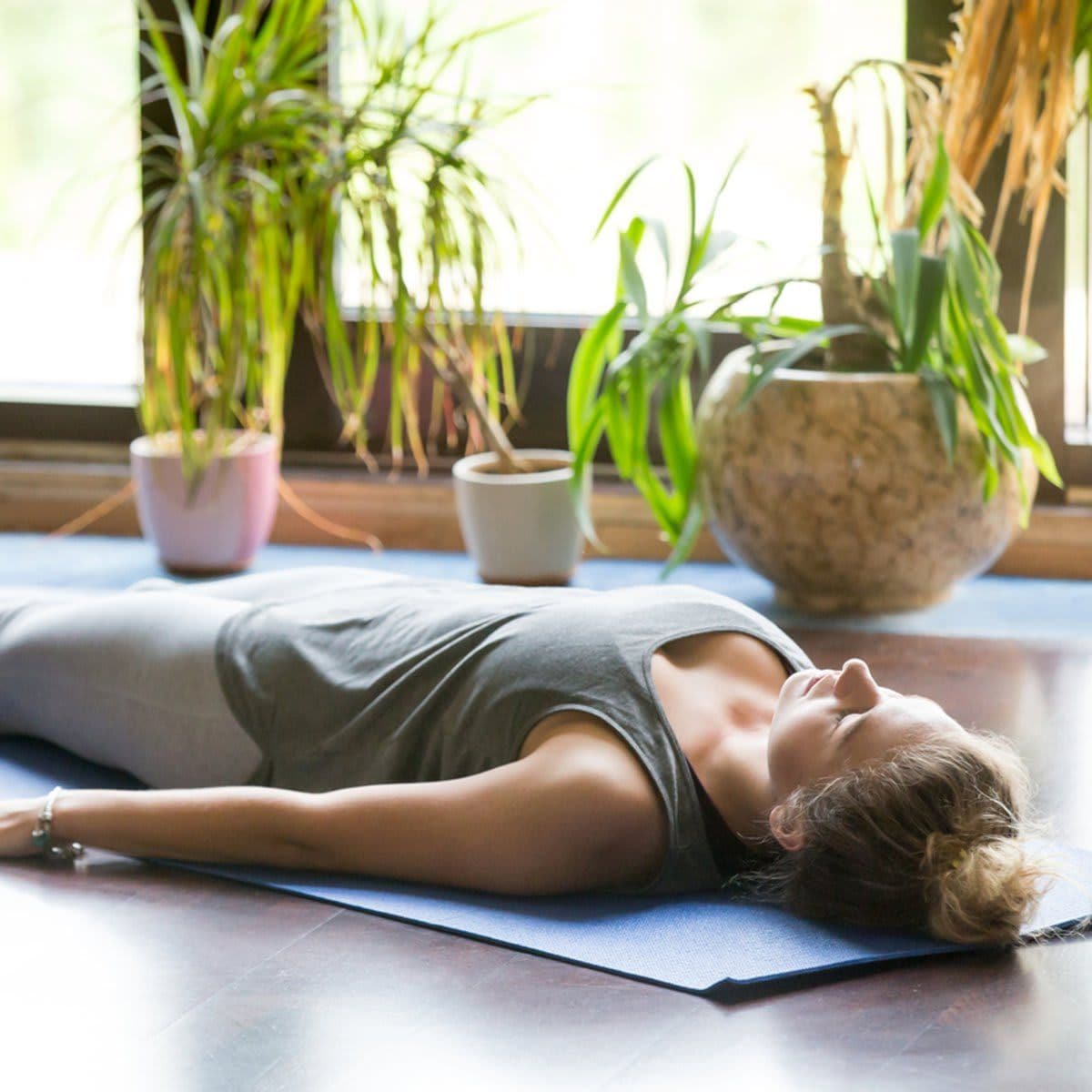 Mujer realiza Yoga sobre mat posición Savasana