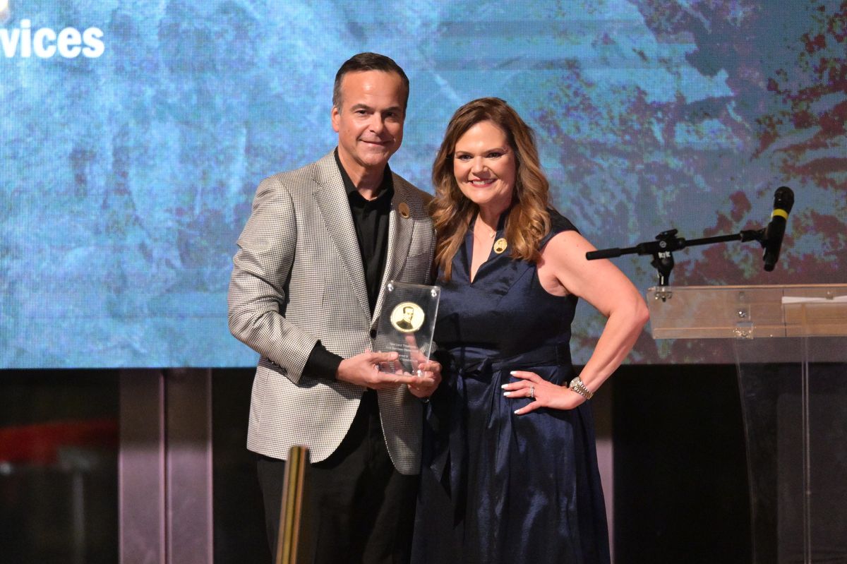 Nancy Batista-Rodriguez presenting an award to Jorge Plasencia during a formal event, both smiling and holding the award together.