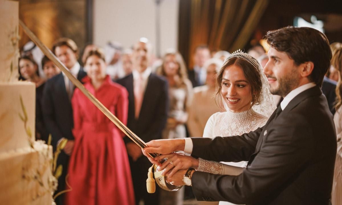 The newlyweds cut their multi-tiered cake with a sword.