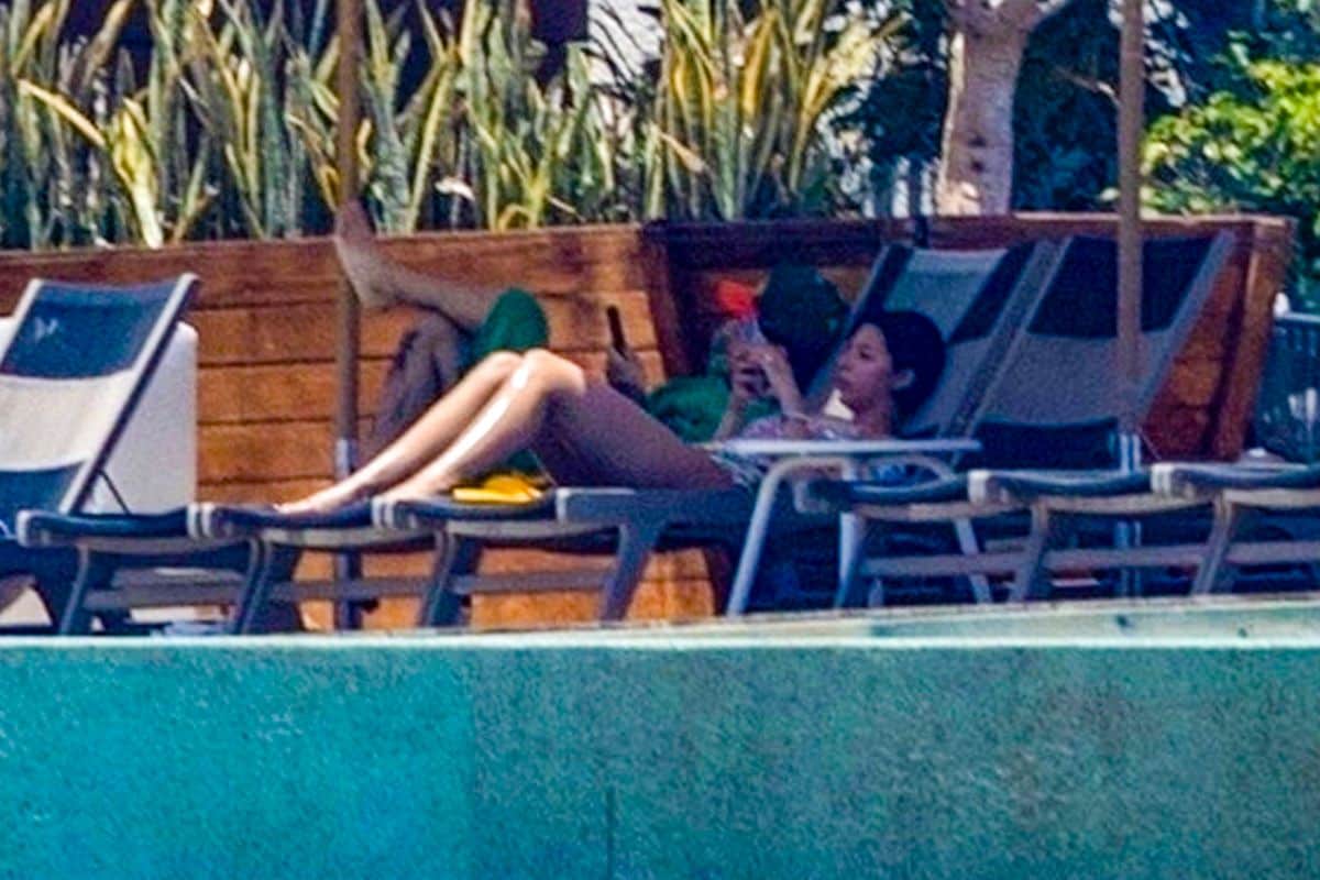 The singers lounged by the pool on their phones