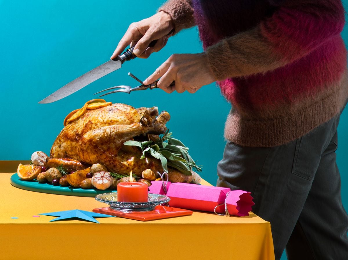 Man carving Christmas turkey at dinner table