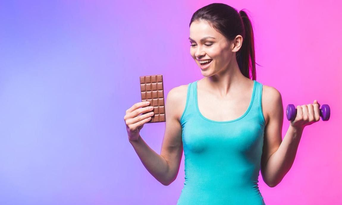 Woman with a bar of chocolate and a dumbbell