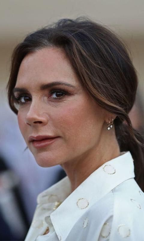 Victoria Beckham' up-do and uniform, natural, and radiant skin