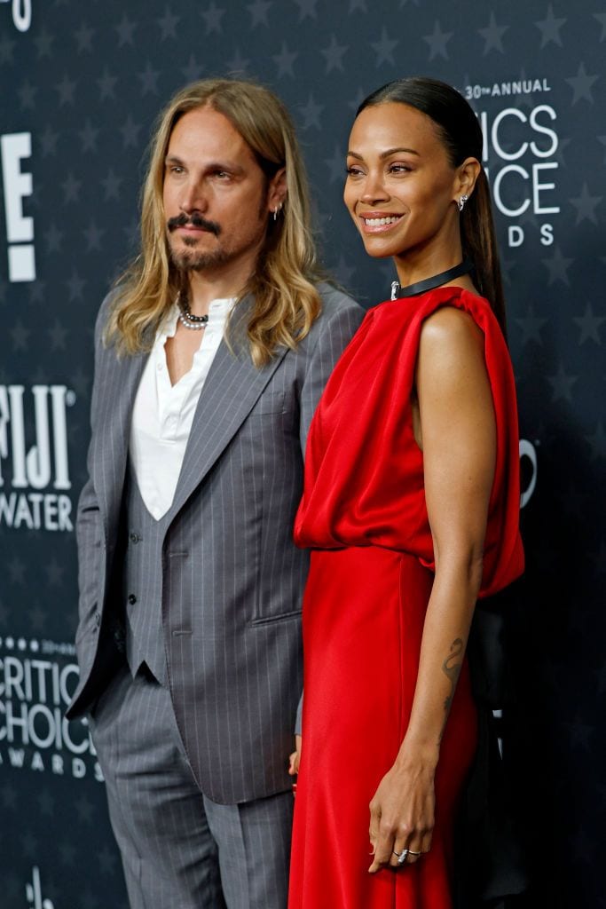 Zoe Saldaña in a stunning red gown poses with her husband, Marco Perego, at the 30th Annual Critics Choice Awards red carpet.