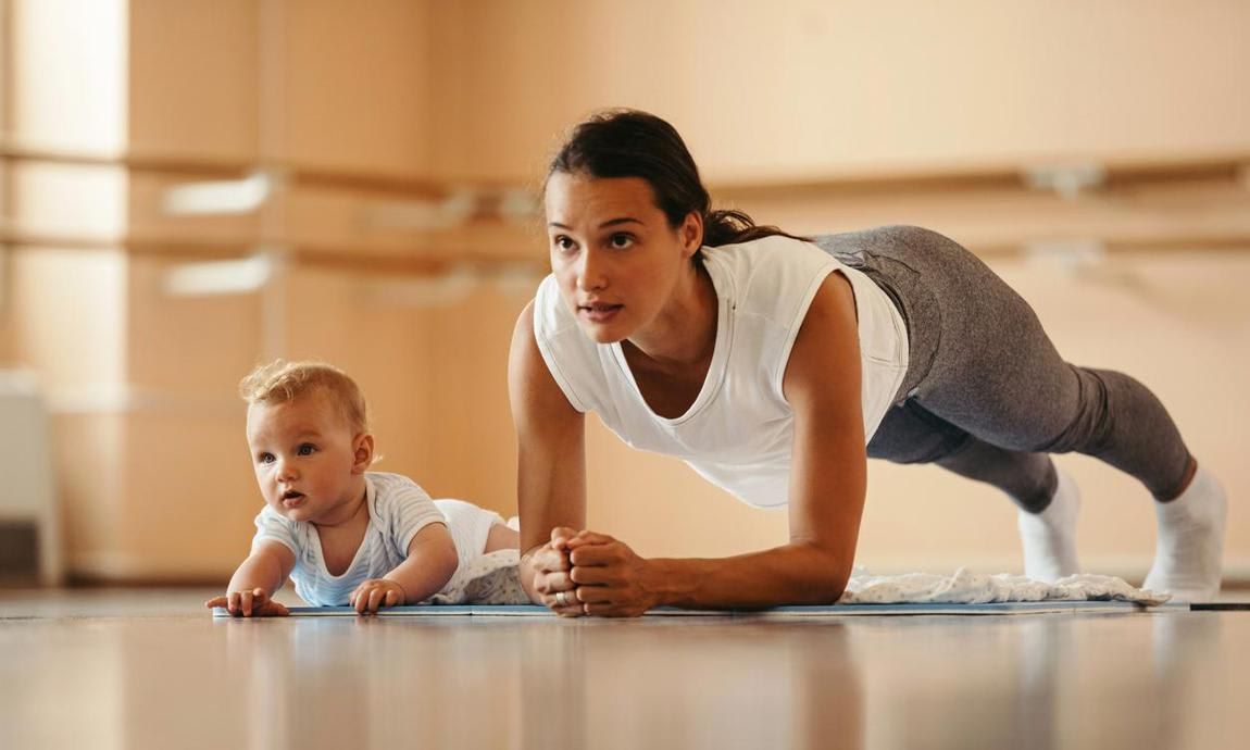 Woman doing a plank with her baby next to her