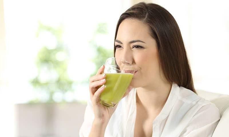 A woman drinking green juice