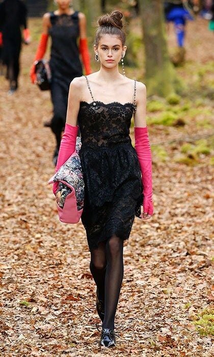 Kaia Gerber walked into the woods during Chanel's Fall/Winter '18 show with a top knot, a black lace dress and popping pink gloves.
Photo: Getty Images