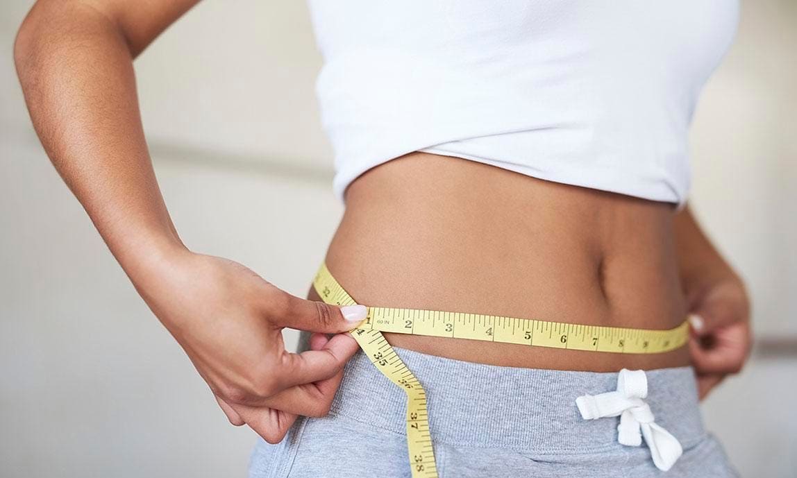 Woman measuring her waist with a tape measure