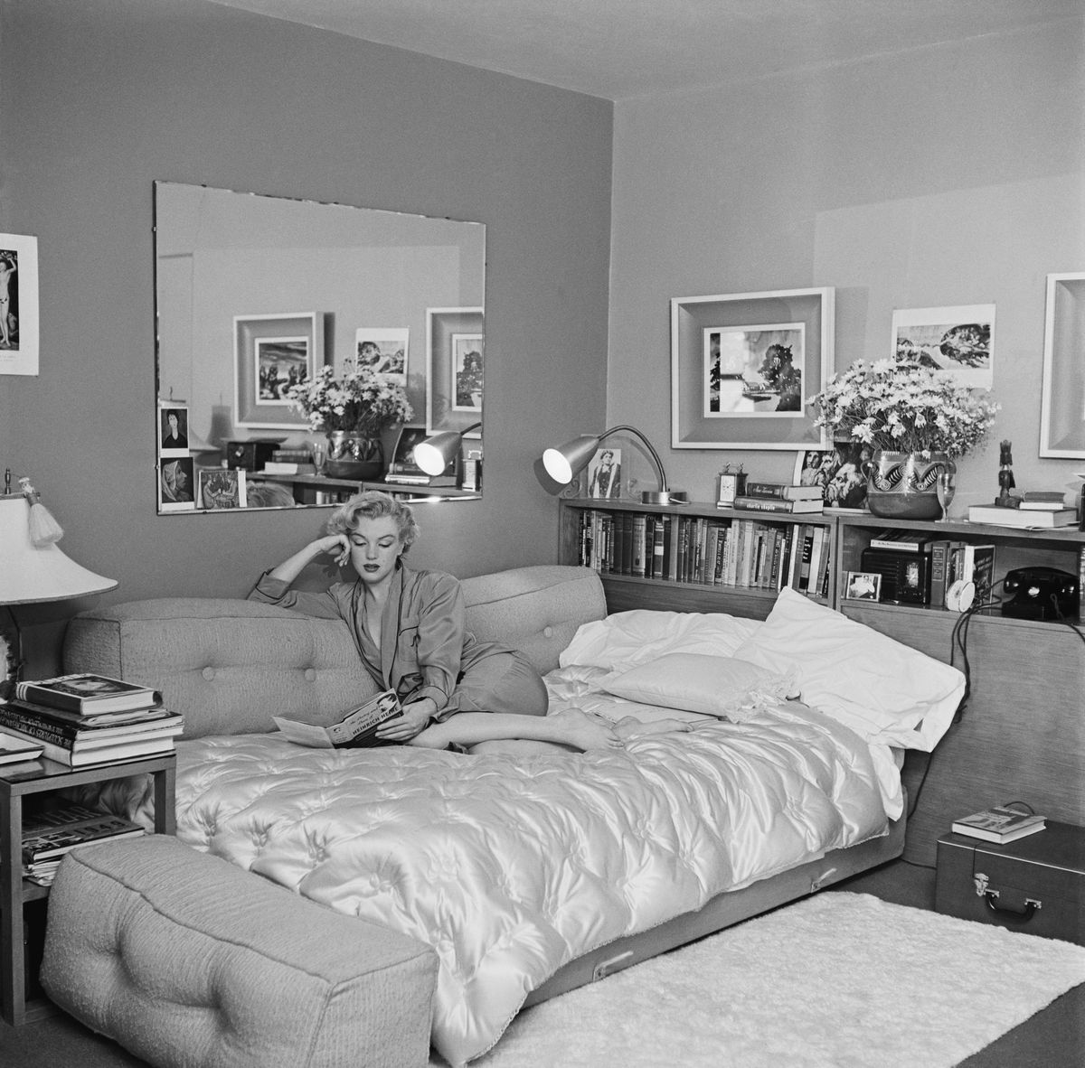 American actress Marilyn Monroe (1926 - 1962) relaxes on a sofa bed in 1951. She is reading 'The Poetry and Prose of Heinrich Heine'. 