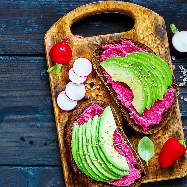 Vegan breakfast avocado and beet rye sandwiches, fresh radishes and sweet pepper