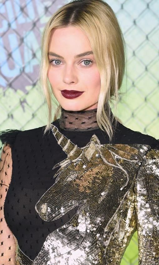 Margot Robbie wears her hair pulled back with two wisps of hair to frame her face