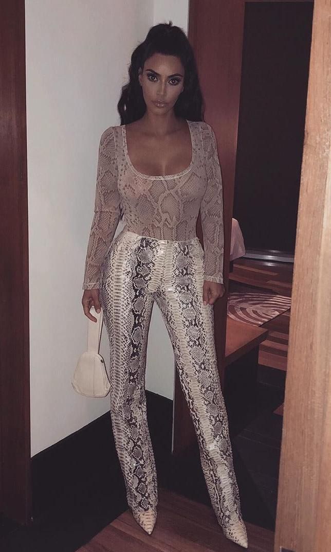 Kim Kardashian in a sheer snakeskin print top with tonal pants and pointed boots