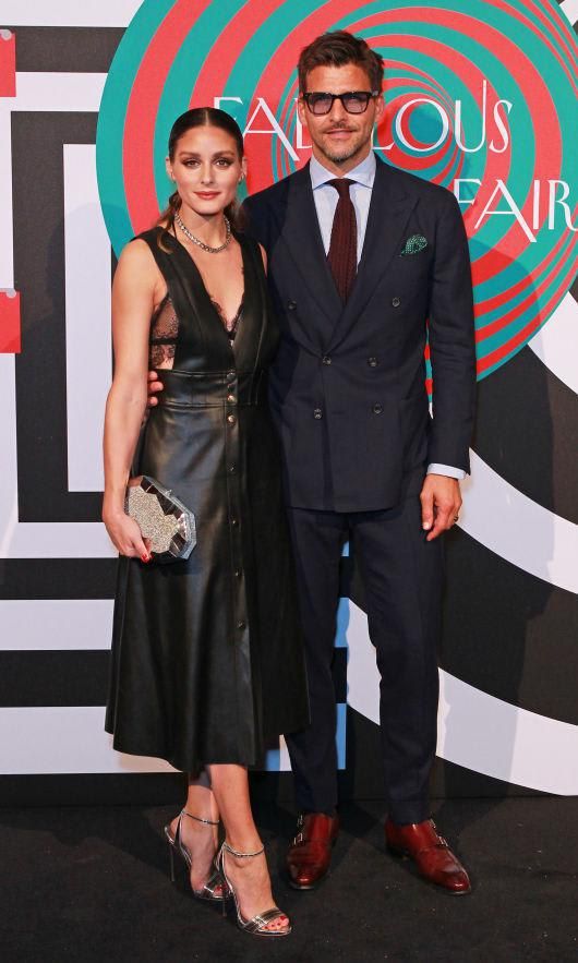 Olivia Palermo in a black leather dress and Johannes Huebl in a dark suit with red shoes