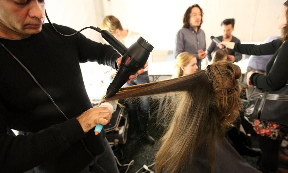 En salon de belleza, estilista seca larga cabellera