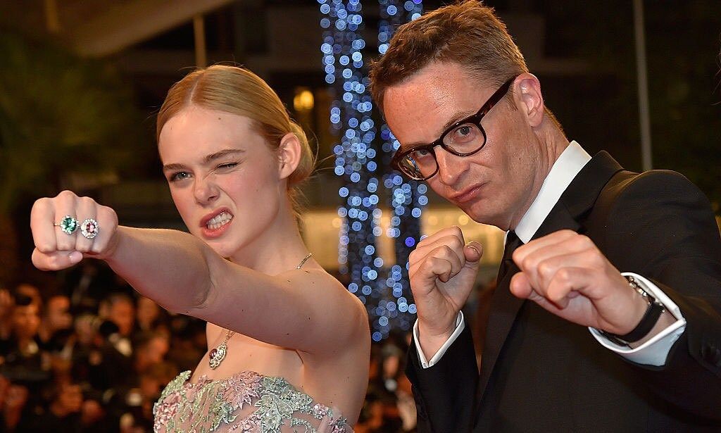 Check out her bling! Elle Fanning flashed her dazzling pink and green rings for the cameras, while posing with Danish director Nicolas Winding Refn on <i>The Neon Demon</i> red carpet.
<br>
Photo: LOIC VENANCE/AFP/Getty Images