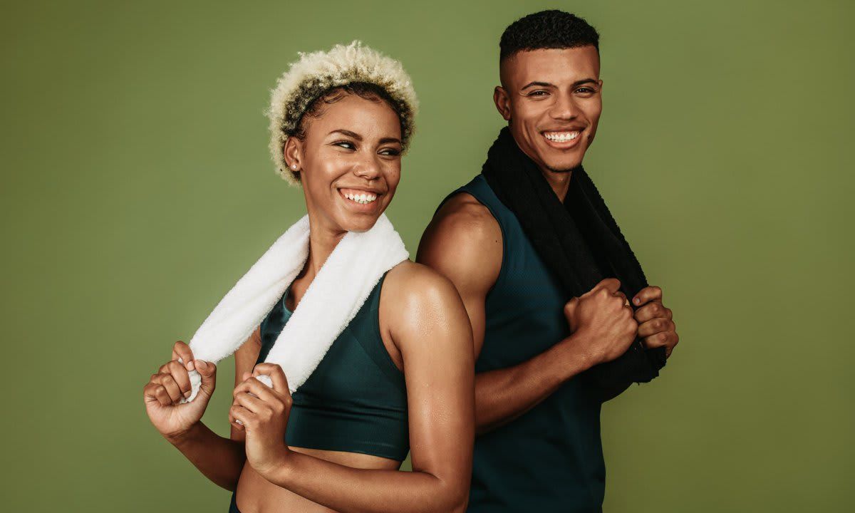 Happy athletic couple standing together holding towels