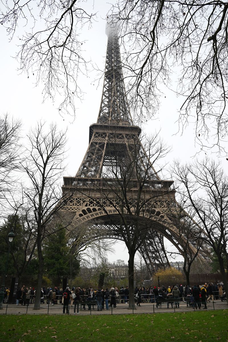 Visitors queue at the bottom of the Eiffel Tower as the site was closed and then reopened after a fire was reported in Paris, on December 24, 2024. (Photo by Anna KURTH / AFP) (Photo by ANNA KURTH/AFP via Getty Images)