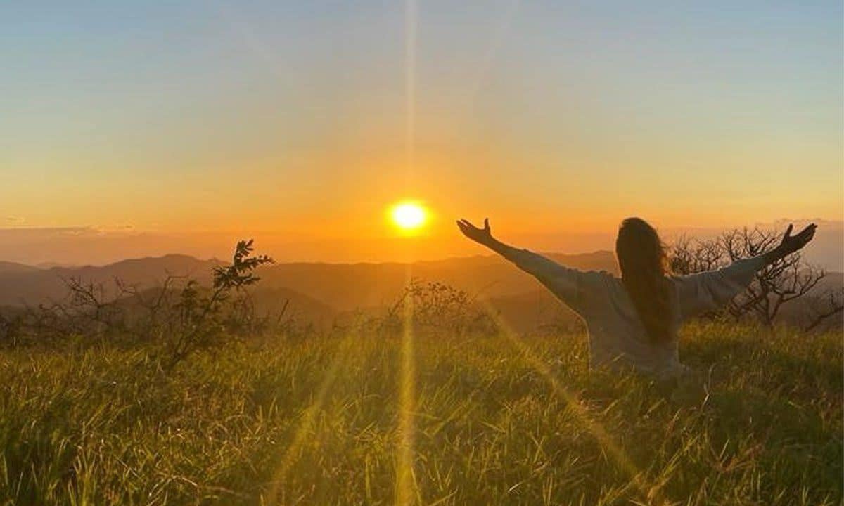 Gisele Bündchen posing in the grass at sunset.