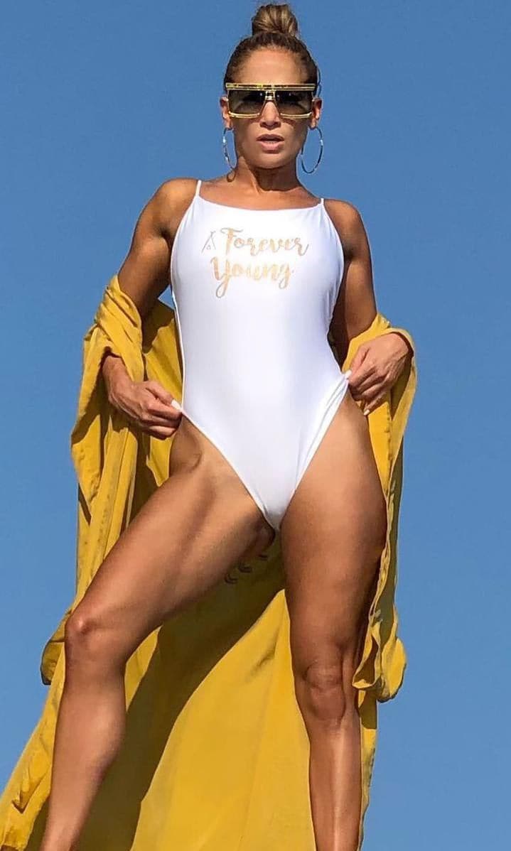 Jennifer Lopez wearing a white swimsuit and gold maxi hoops