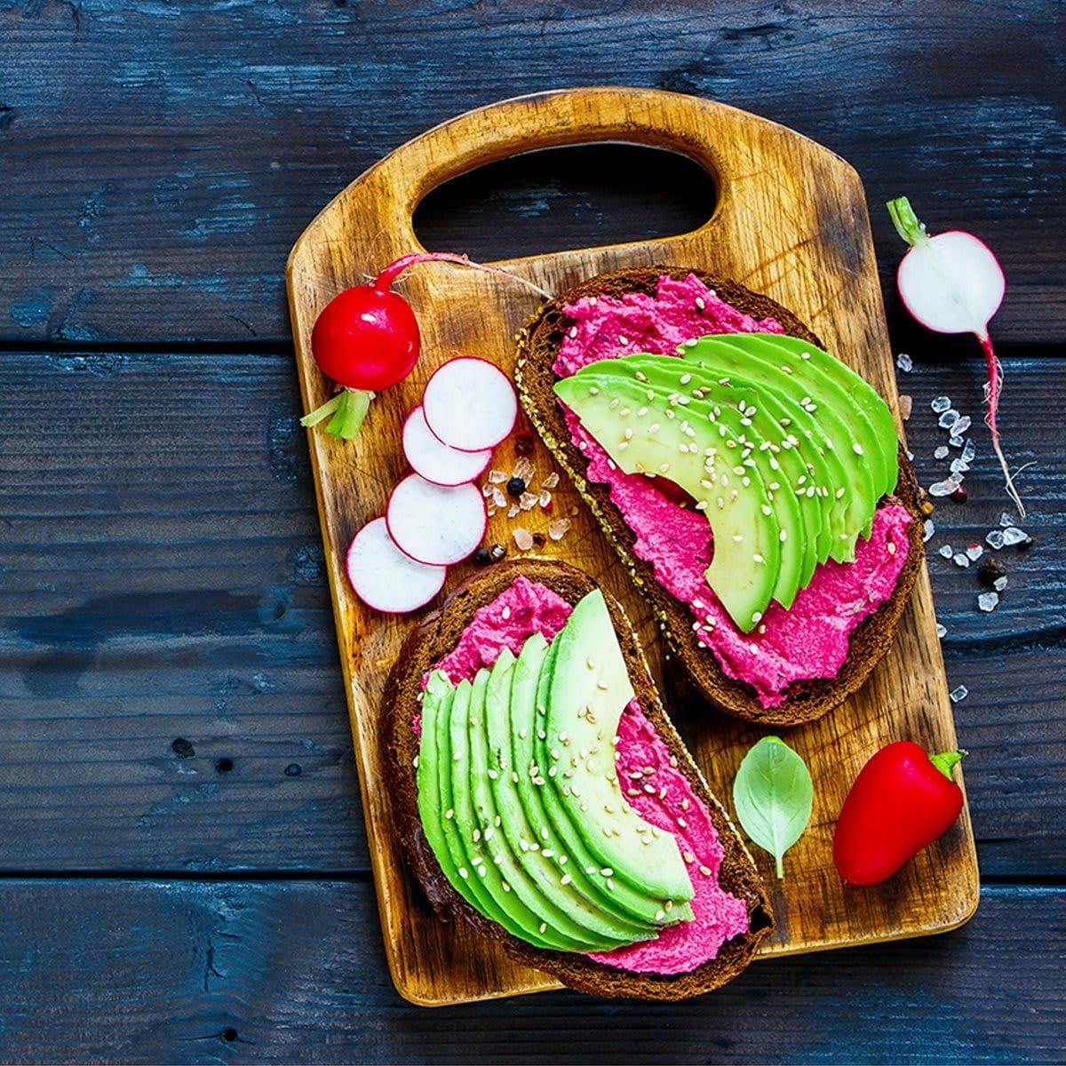 Vegan breakfast avocado and beet rye sandwiches, fresh radishes and sweet pepper