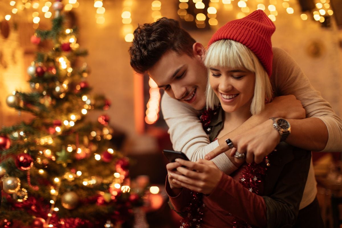 Couple hugging and using smartphone at New Year's party