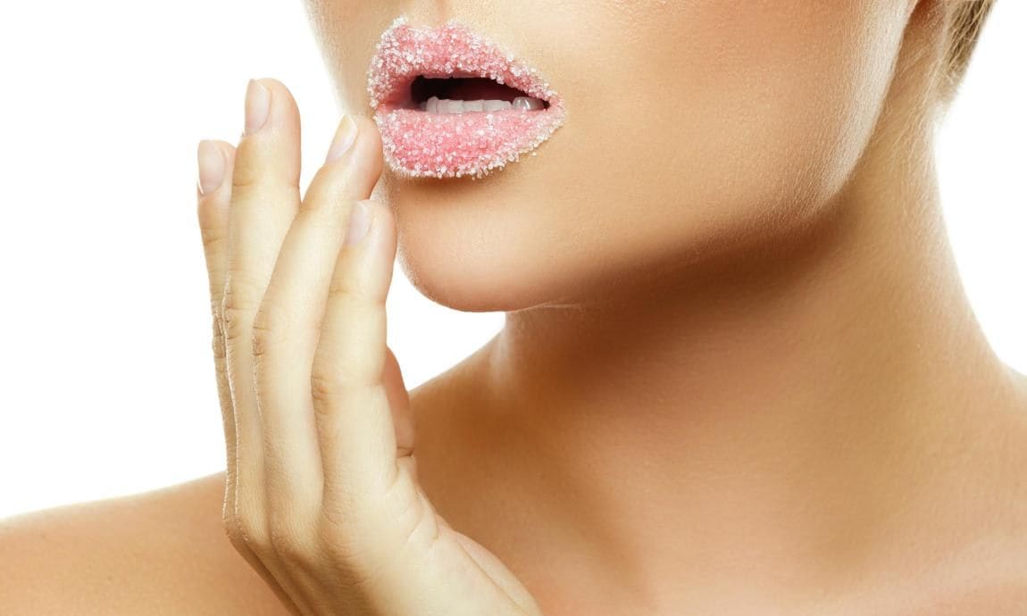 Woman applying natural scrub to her lips.