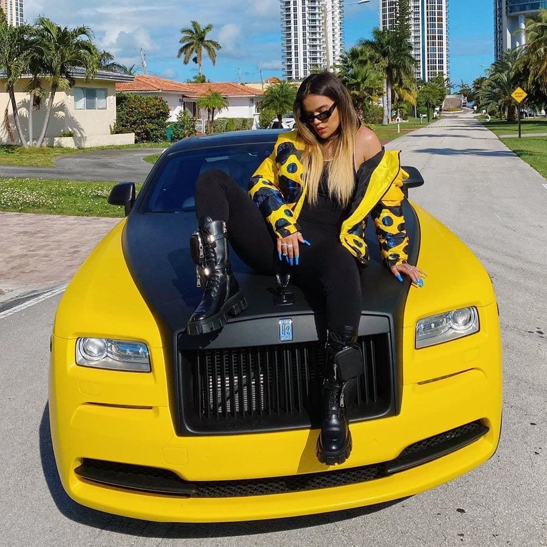 Karol G posing on top of her Rolls Royce, gifted by boyfriend Anuel AA