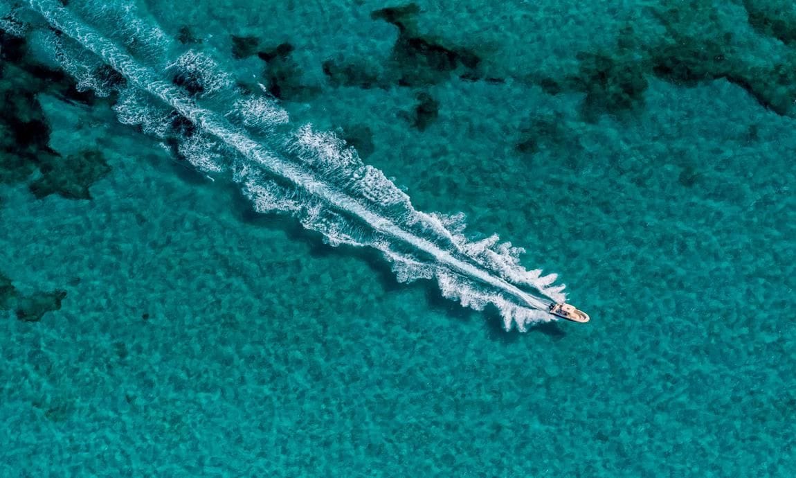 A boat crosses turquoise seas