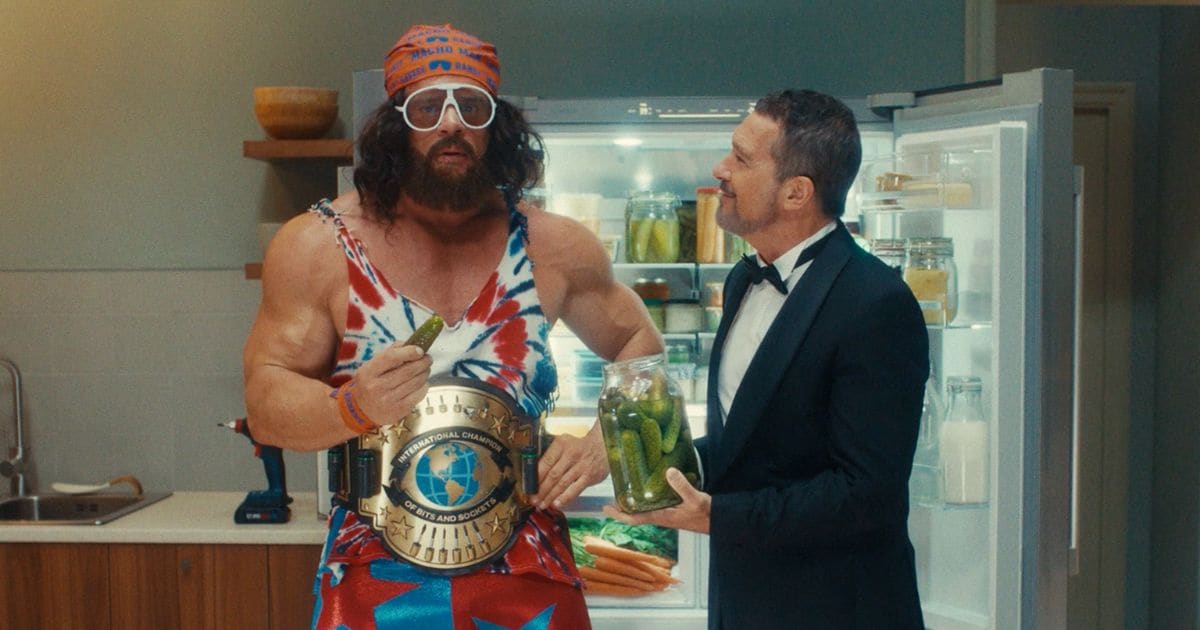 Antonio Banderas in a tuxedo stands in front of an open Bosch refrigerator, holding a carrot in a Super Bowl commercial.