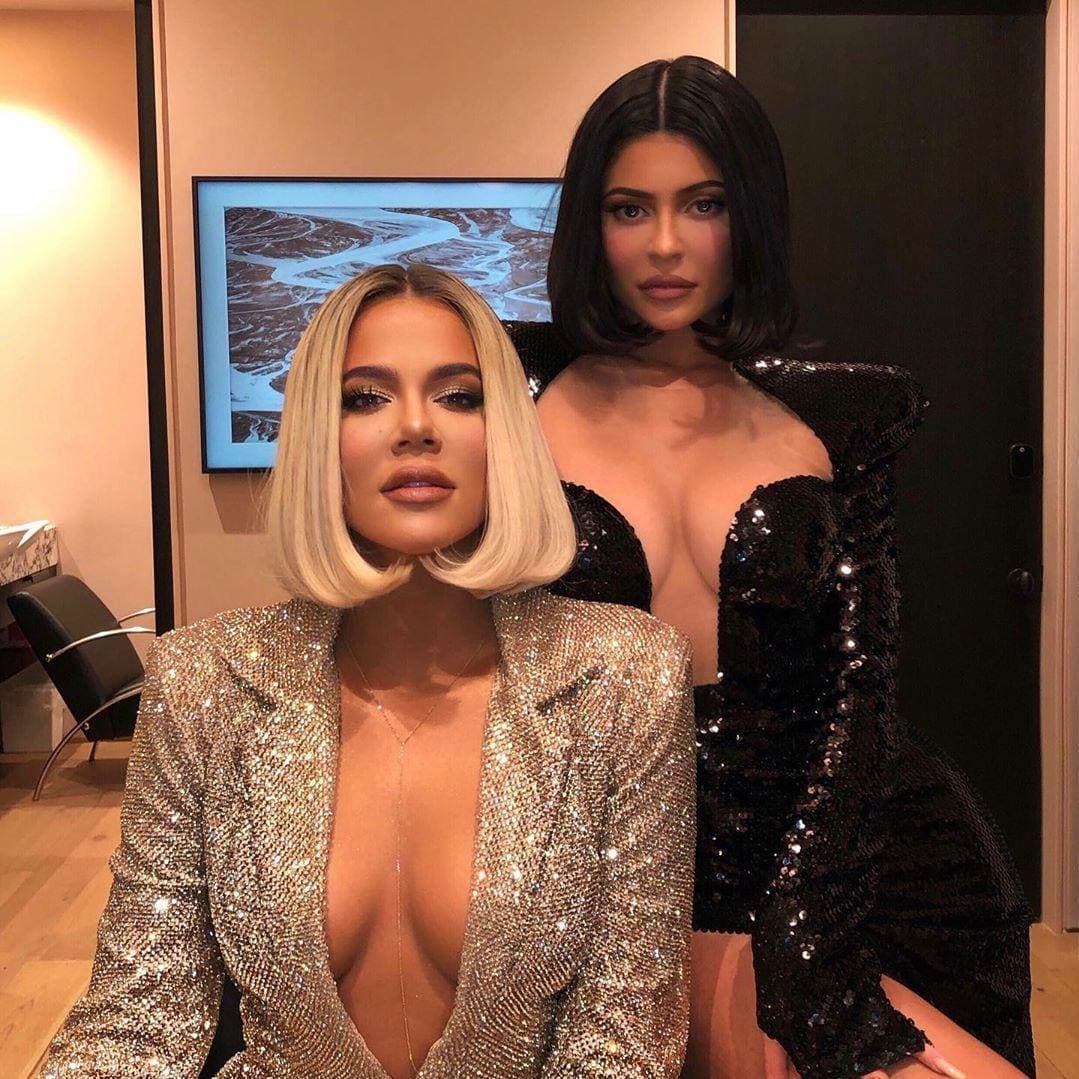 Khloé Kardashian with blond hair and Kylie Jenner with dark brown hair, both wearing a bob cutn