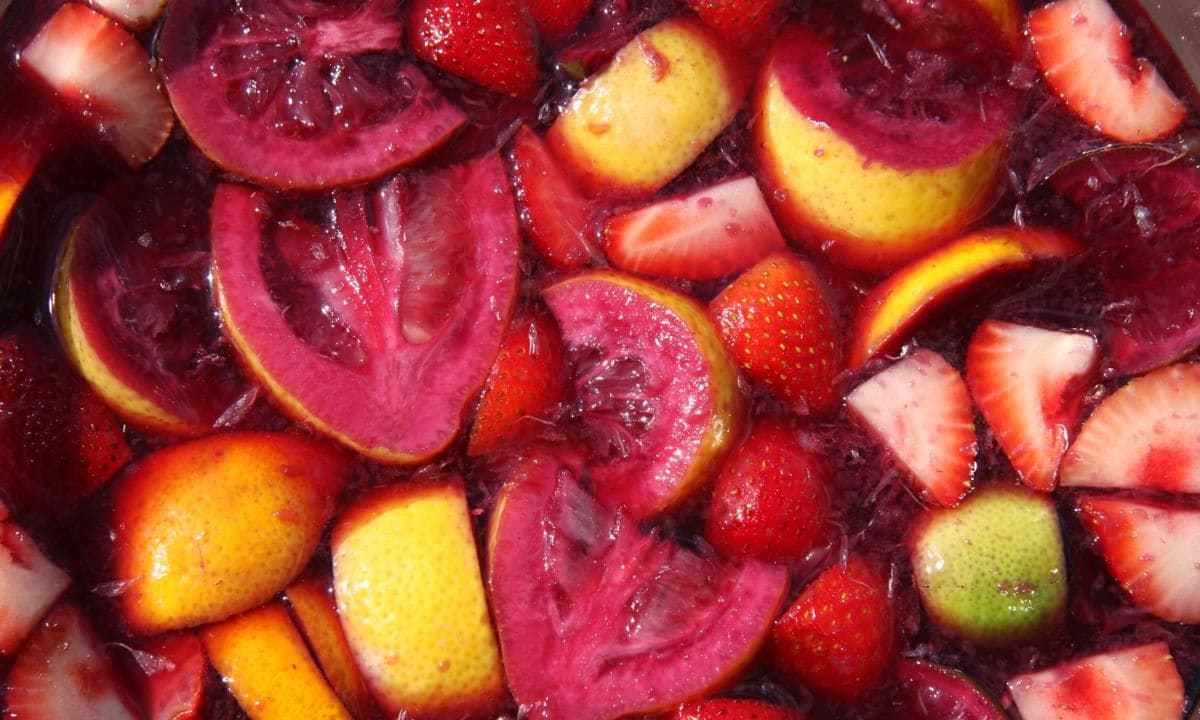 Fruit of Sangria, oranges, pineapple, strawberries and lime, floating in pool of wine.