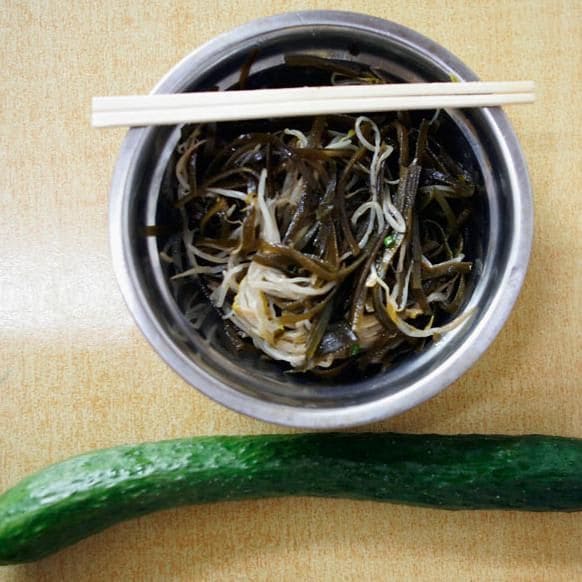 A bowl of shredded kelp with soy sauce and a cucumber