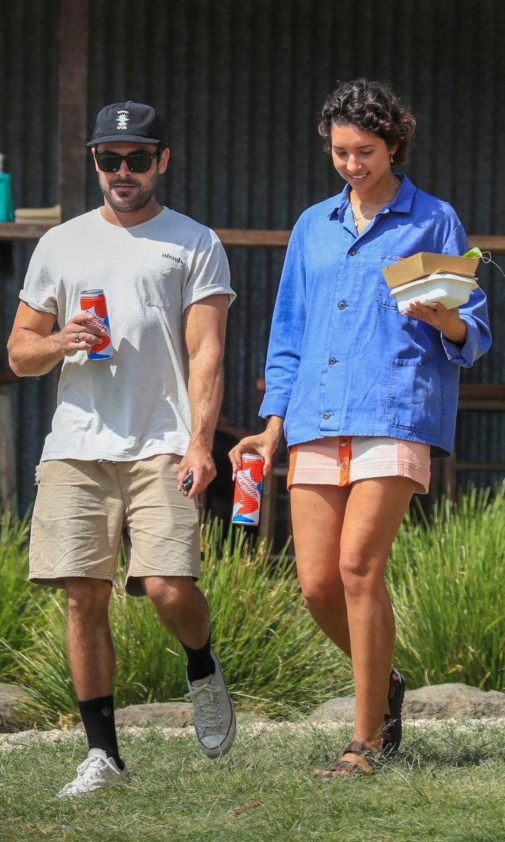 Zac Efron in white shirt and hats holds hand with Vanessa Valladares on a lunch outing in Byron Bay.