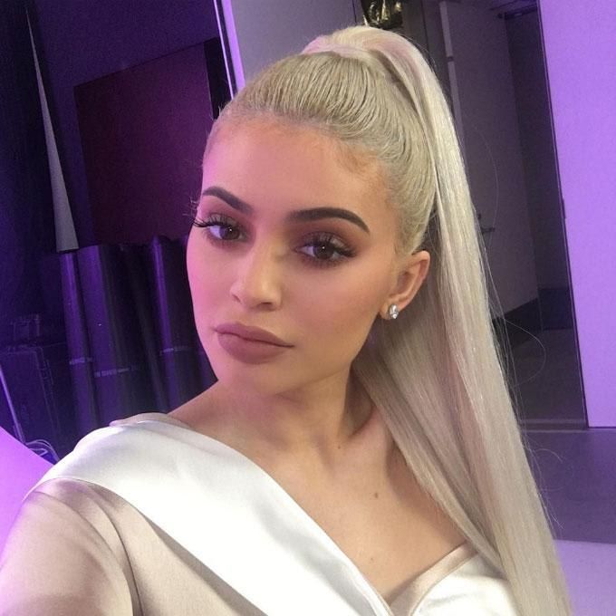 Kylie Jenner poses for a selfie with a blonde ponytail and makeup in brown shades