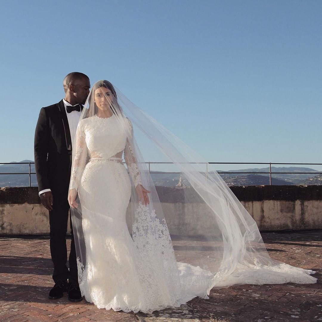 Kim Kardashian poses with her husband, Kanye West, in her high-fashion wedding dress by Givenchy
