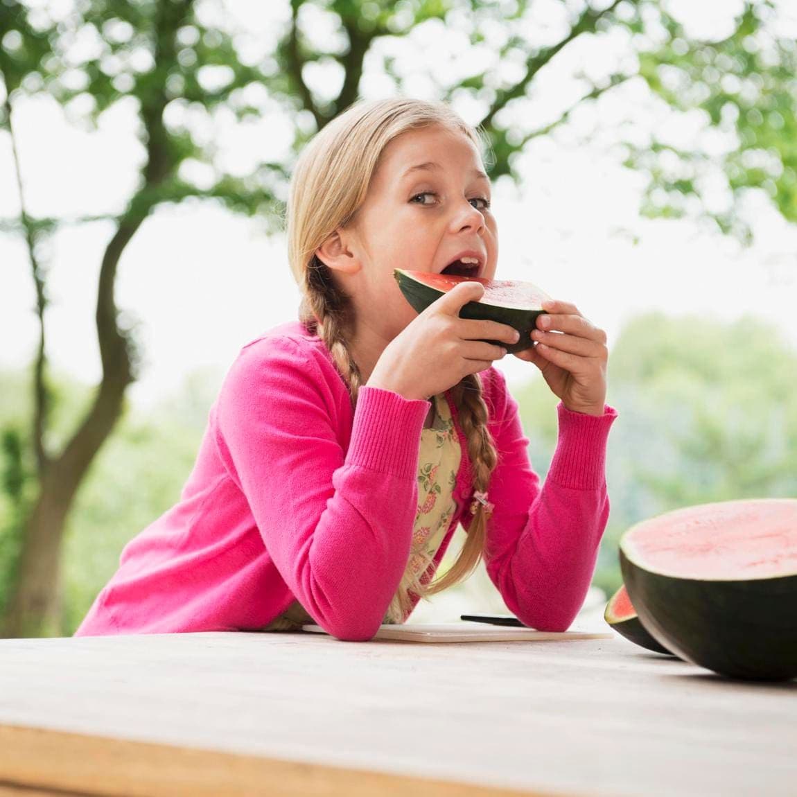 A girl outside eating a watermelon wedge