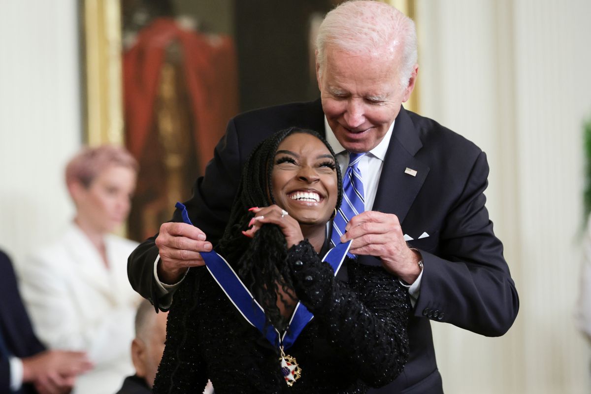 WASHINGTON, DC - JULY 7: U.S. President Joe Biden presents the Presidential Medal of Freedom to Simone Biles, Olympic gold medal gymnast and mental health advocate, during a ceremony in the East Room of the White House July 7, 2022 in Washington, DC. President Biden awarded the nation's highest civilian honor to 17 recipients. The award honors individuals who have made exemplary contributions to the prosperity, values, or security of the United States, world peace, or other significant societal, public or private endeavors. (Photo by Alex Wong/Getty Images)