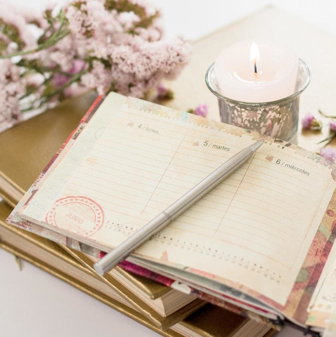 Planner with pen, flowers and a candle.