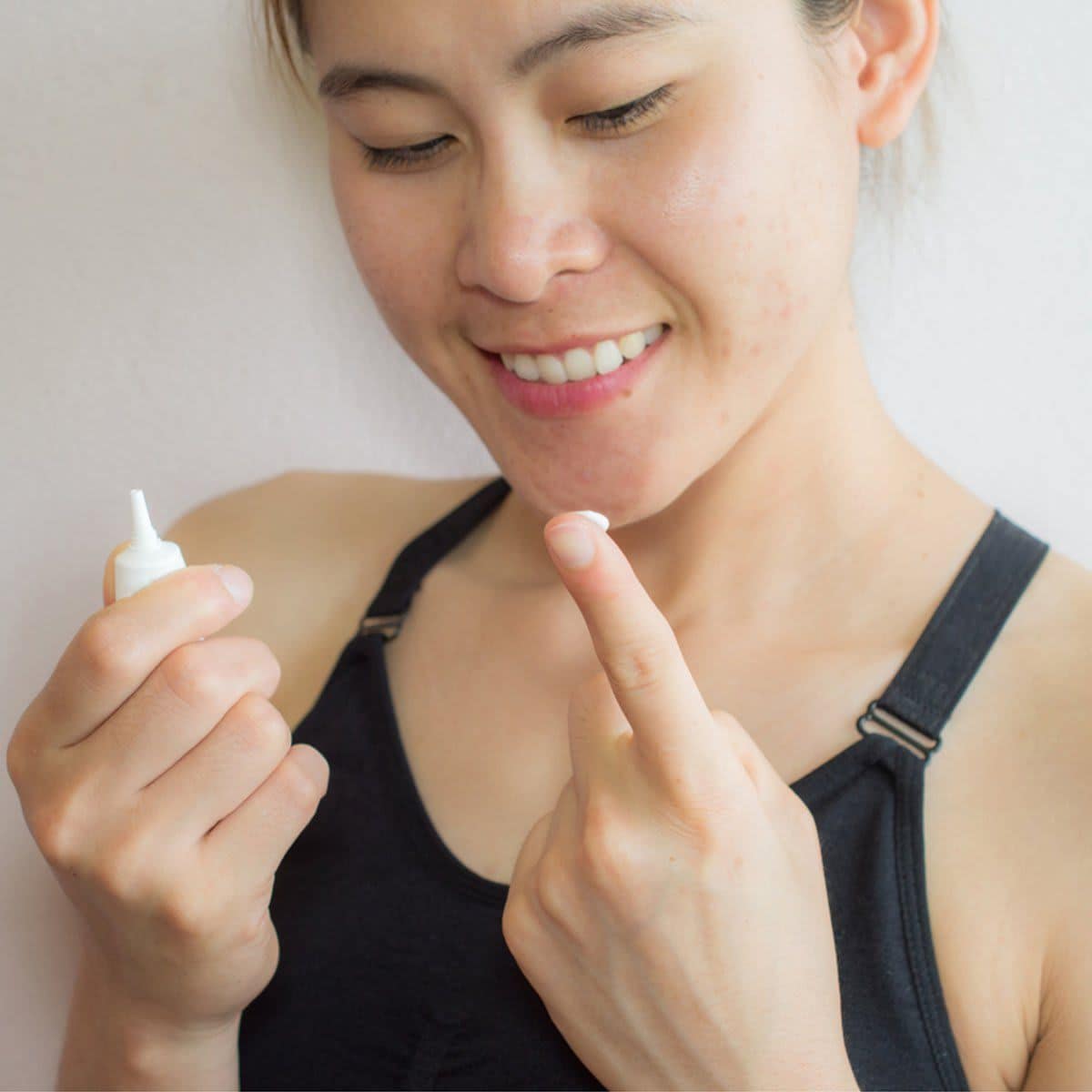 Shot of woman preparing for applying acne cream for solve her problem skin