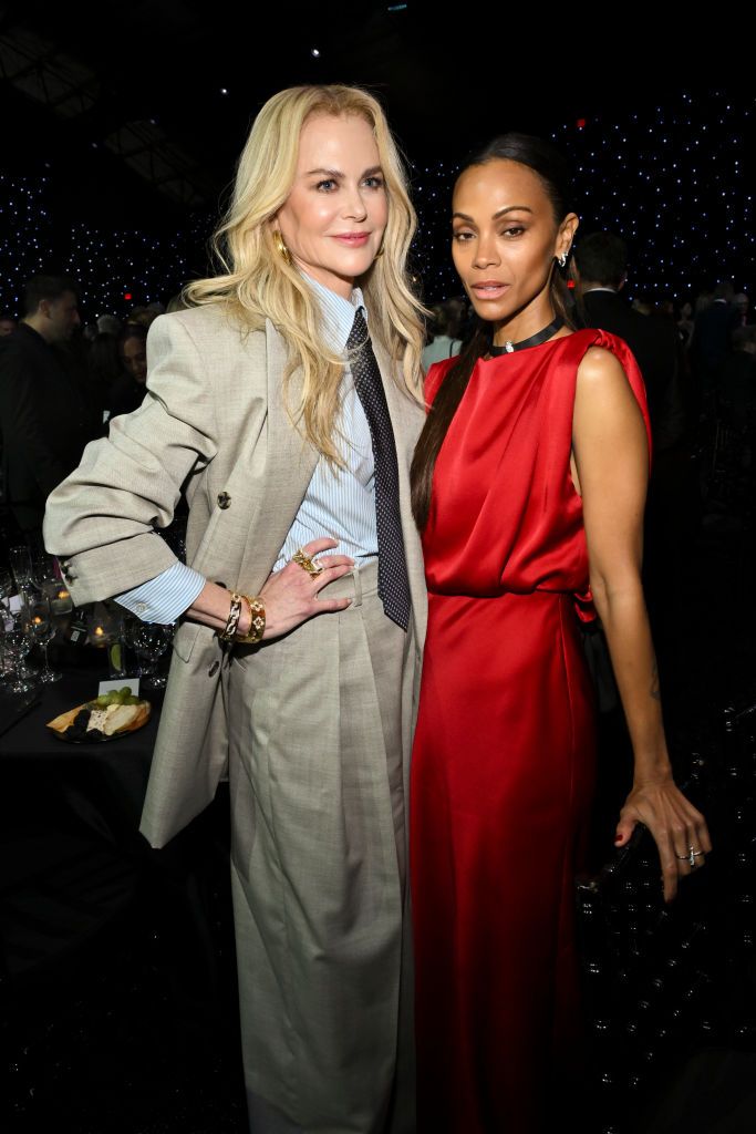 Nicole Kidman and Zoe Saldaña pose together at the Critics Choice Awards, with Saldaña in a red gown and Kidman in a chic beige suit.