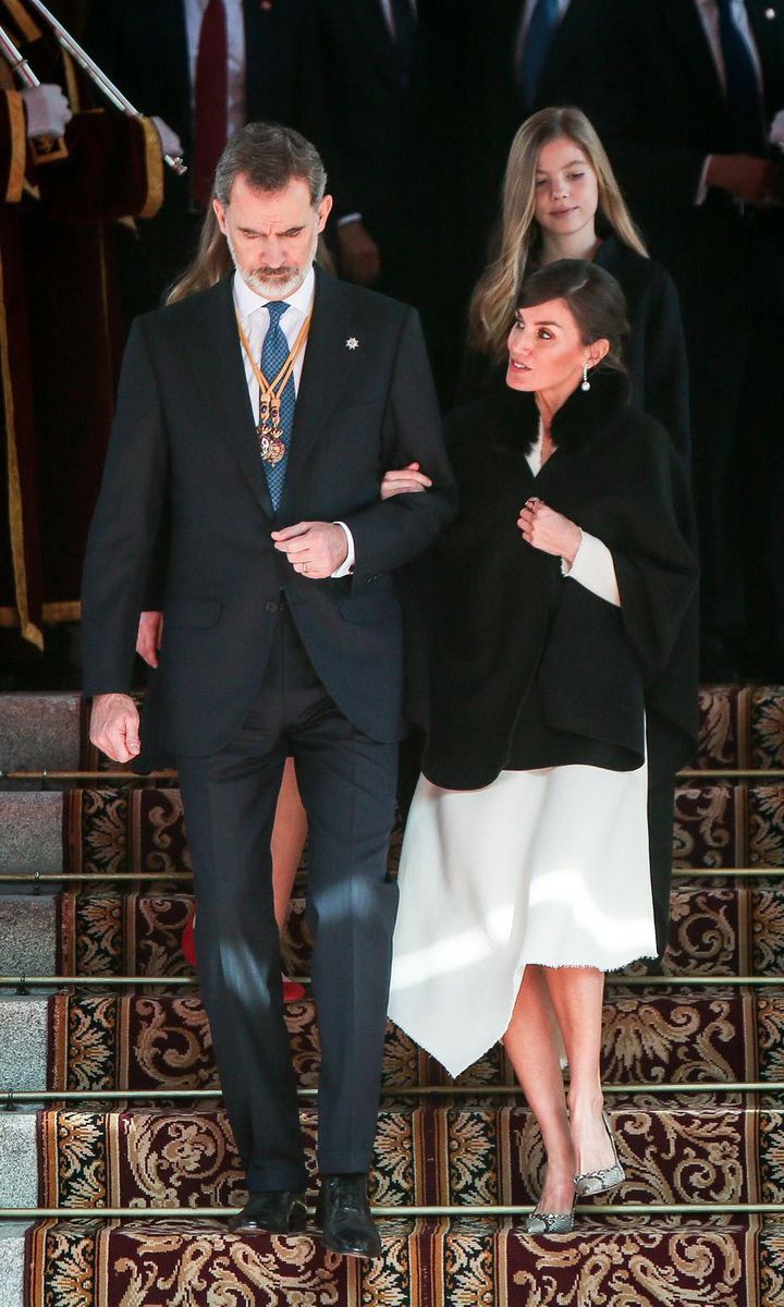 King Felipe gave his wife a hand during the outing on February 3. The Queen wore a sophisticated white dress designed with an asymmetrical hem beneath her cape.