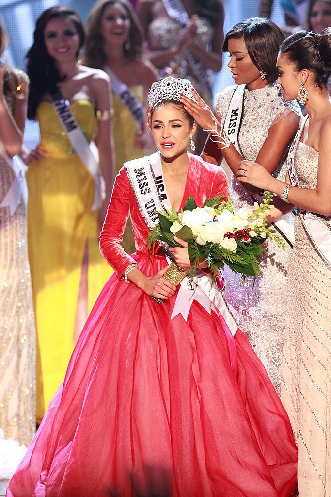 Olivia Culpo crowned Miss Universe 2012 in a red gown, holding a bouquet.